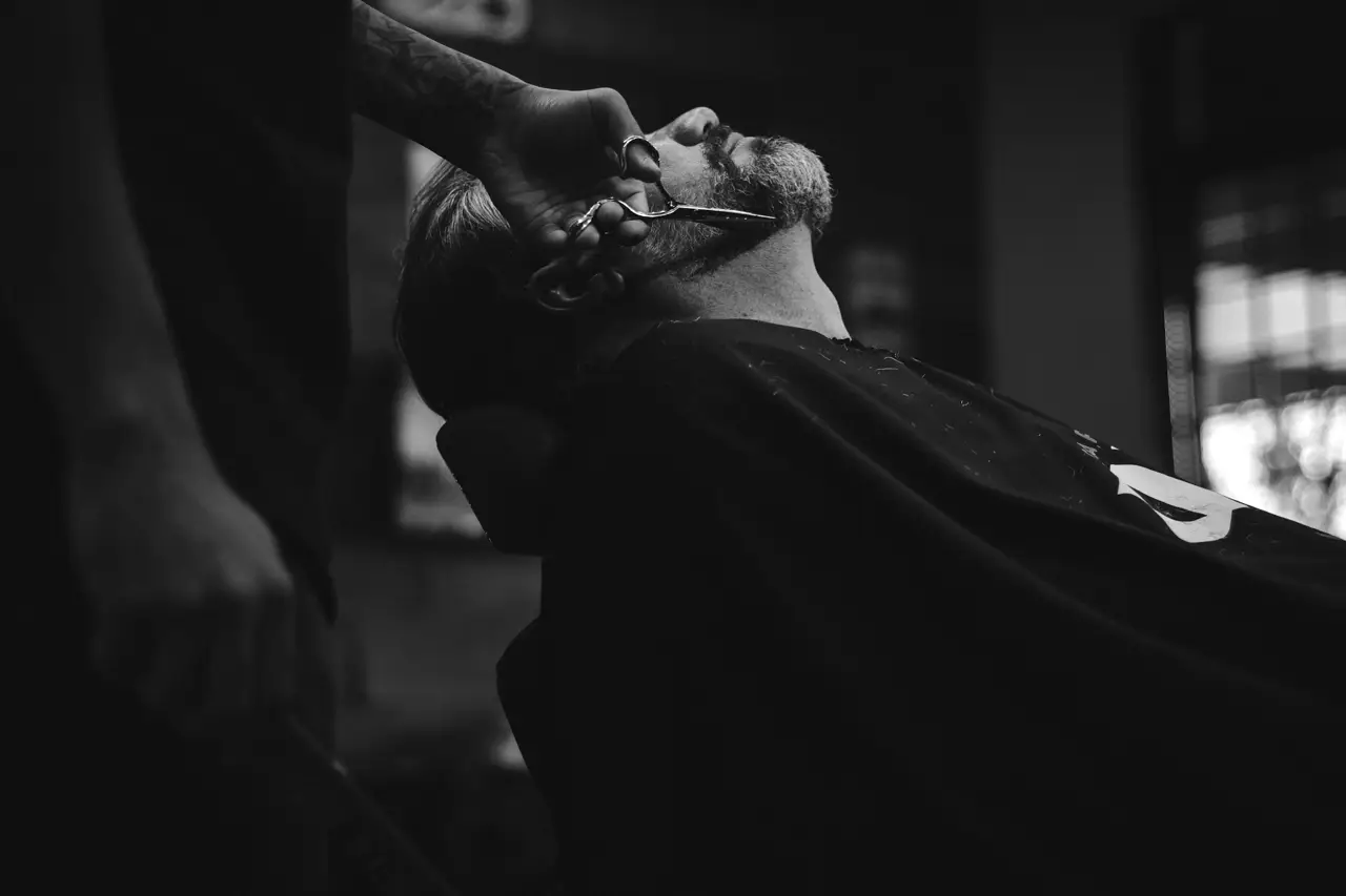 Barbero afeitando a un cliente con navaja